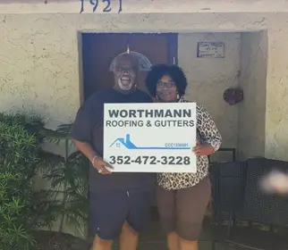 Client smiling in front of their newly installed roof by Worthmann Roofing